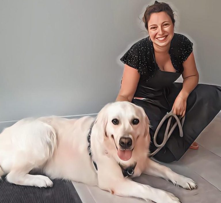 Femme souriante à genoux à côté d'un labrador retriever allongé.